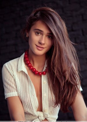 Сольная модель Райя уверенно демонстрирует свою обнаженную красоту на красном диване